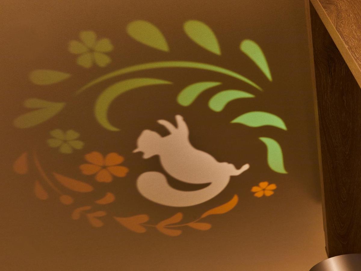 Grand Nikko Tokyo Bay Maihama Urayasu Exterior foto The photo shows a colorful projection on a surface that includes a playful illustration. The design features a white silhouette of a squirrel in a lively pose, surrounded by decorative elements like green leaves and flowers in shades of orange and ye