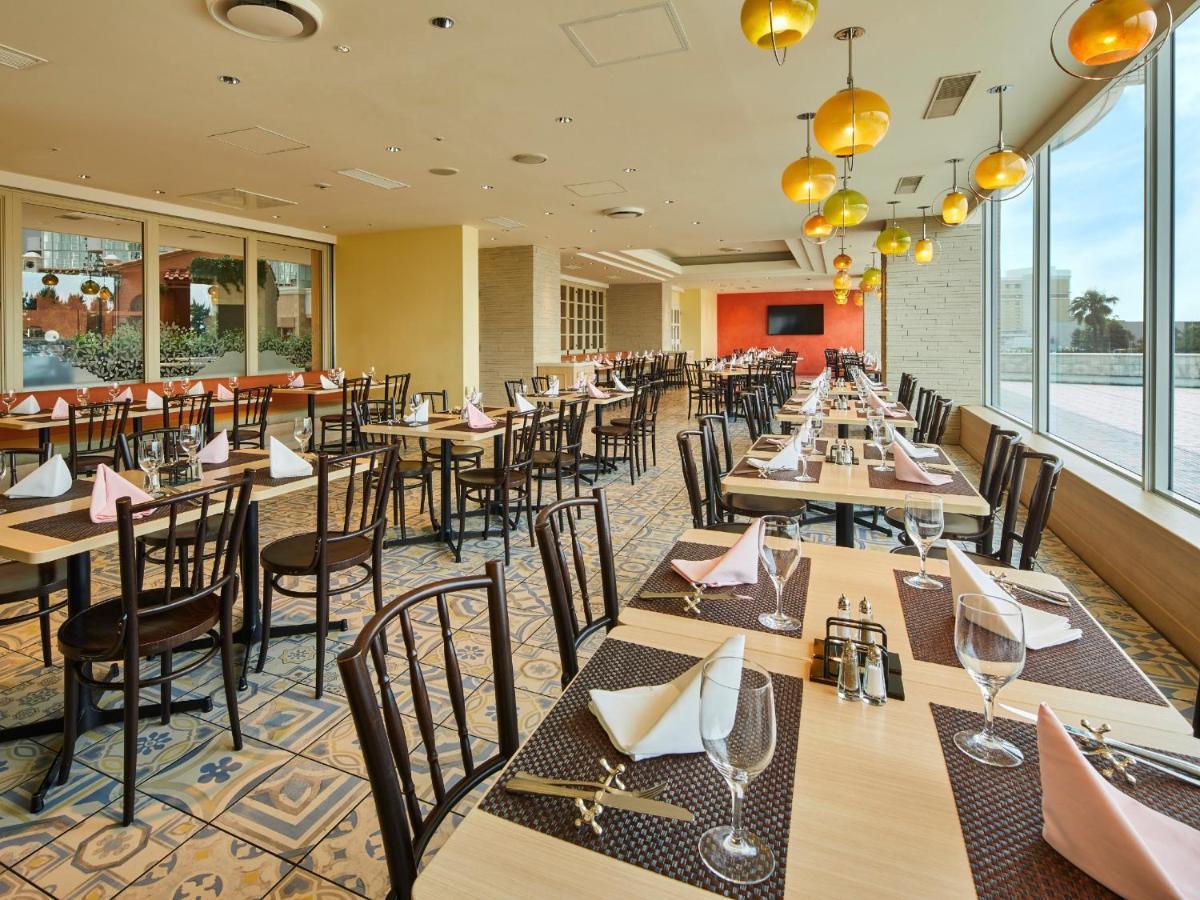 Grand Nikko Tokyo Bay Maihama Urayasu Exterior foto The photo shows a spacious restaurant interior with multiple wooden tables arranged neatly. Each table is set with plates, glasses, and folded napkins, suggesting it's prepared for dining. The decor features large windows allowing natural light to fl