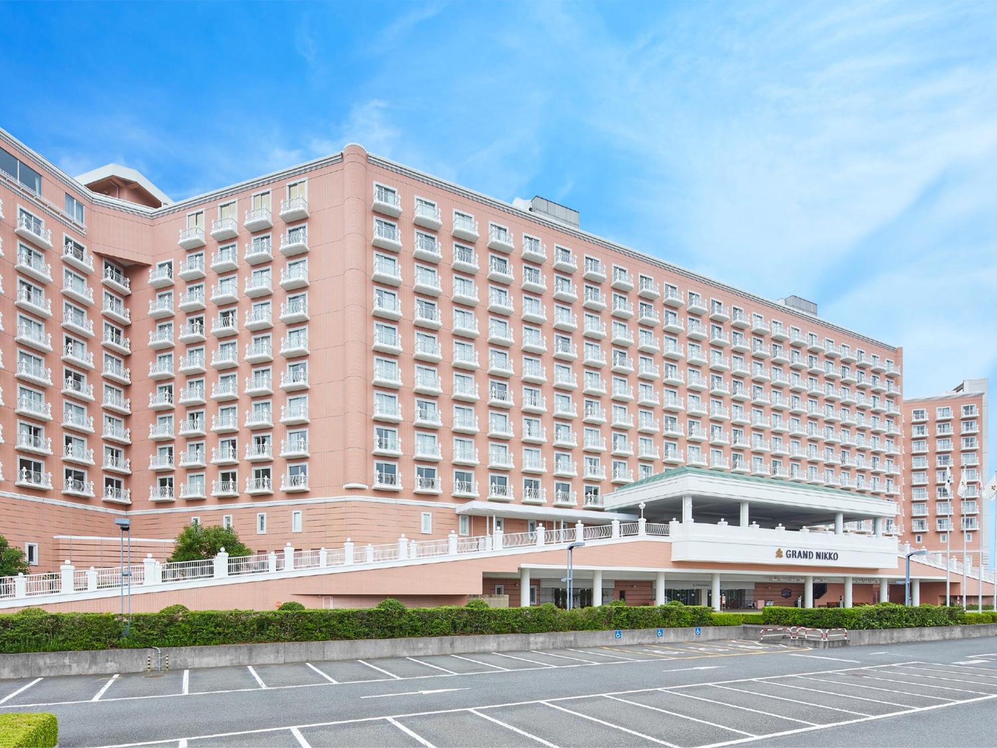 Grand Nikko Tokyo Bay Maihama Urayasu Exterior foto The photo shows a large, multi-story hotel building, characterized by its pink facade and modern architectural design. The structure features numerous windows and a spacious entrance area, complemented by a canopy. In front of the hotel, there is a p