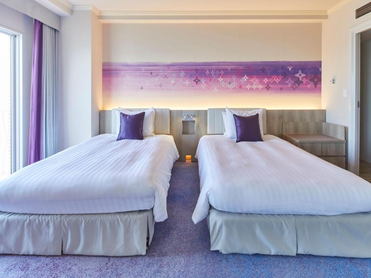 Grand Nikko Tokyo Bay Maihama Urayasu Exterior foto The photo shows a hotel room featuring two twin beds with white bedding and purple accent pillows. The beds are positioned next to each other, with a light-colored headboard. Behind the beds, there is a decorative wall with a gradient of purple hues.