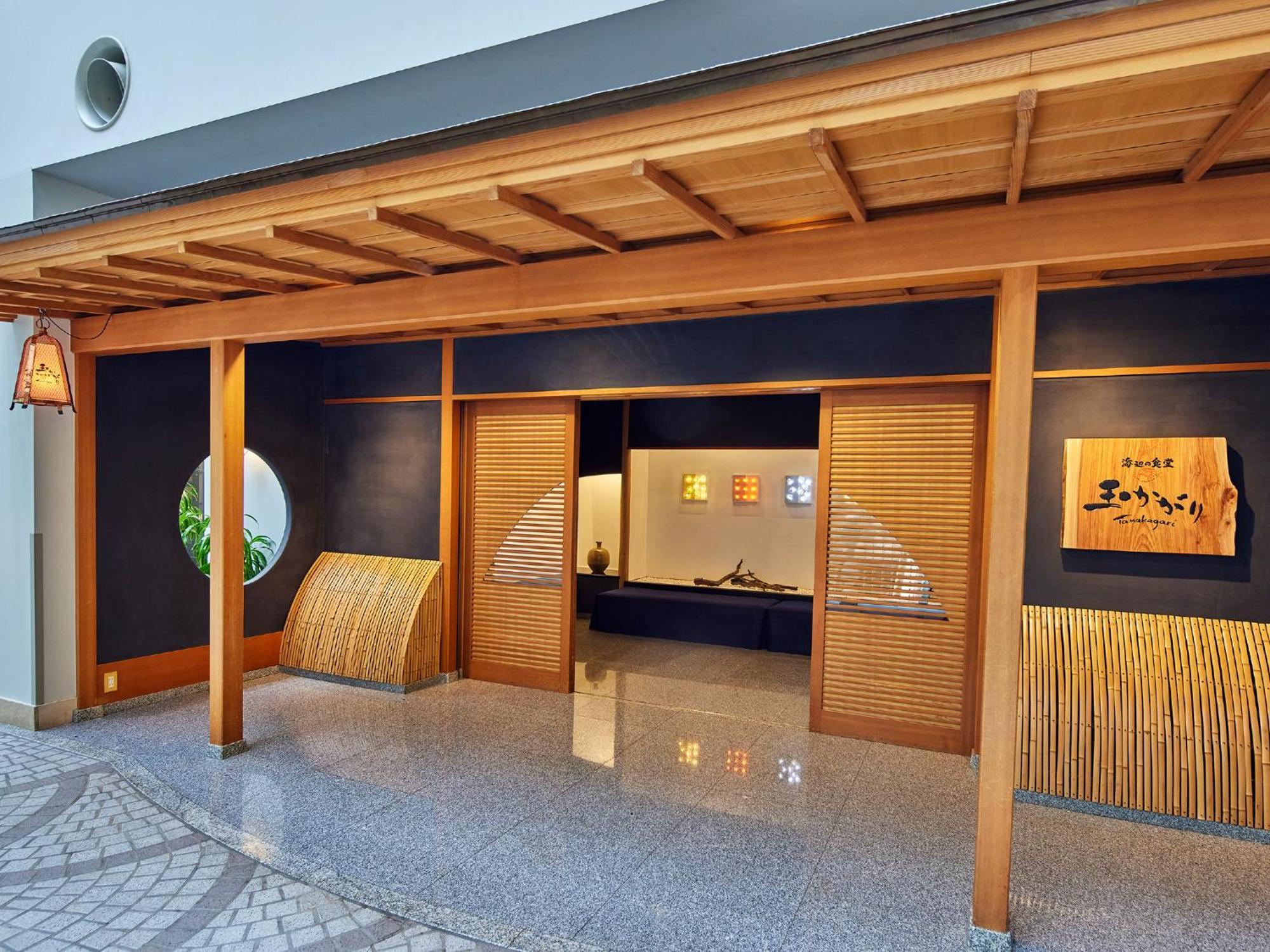 Grand Nikko Tokyo Bay Maihama Urayasu Exterior foto The photo shows the entrance of a building, designed in a traditional Japanese style. It features a wooden structure with a large overhanging roof and sliding doors. The entrance is flanked by rounded windows, and there's a decorative sign with Japan