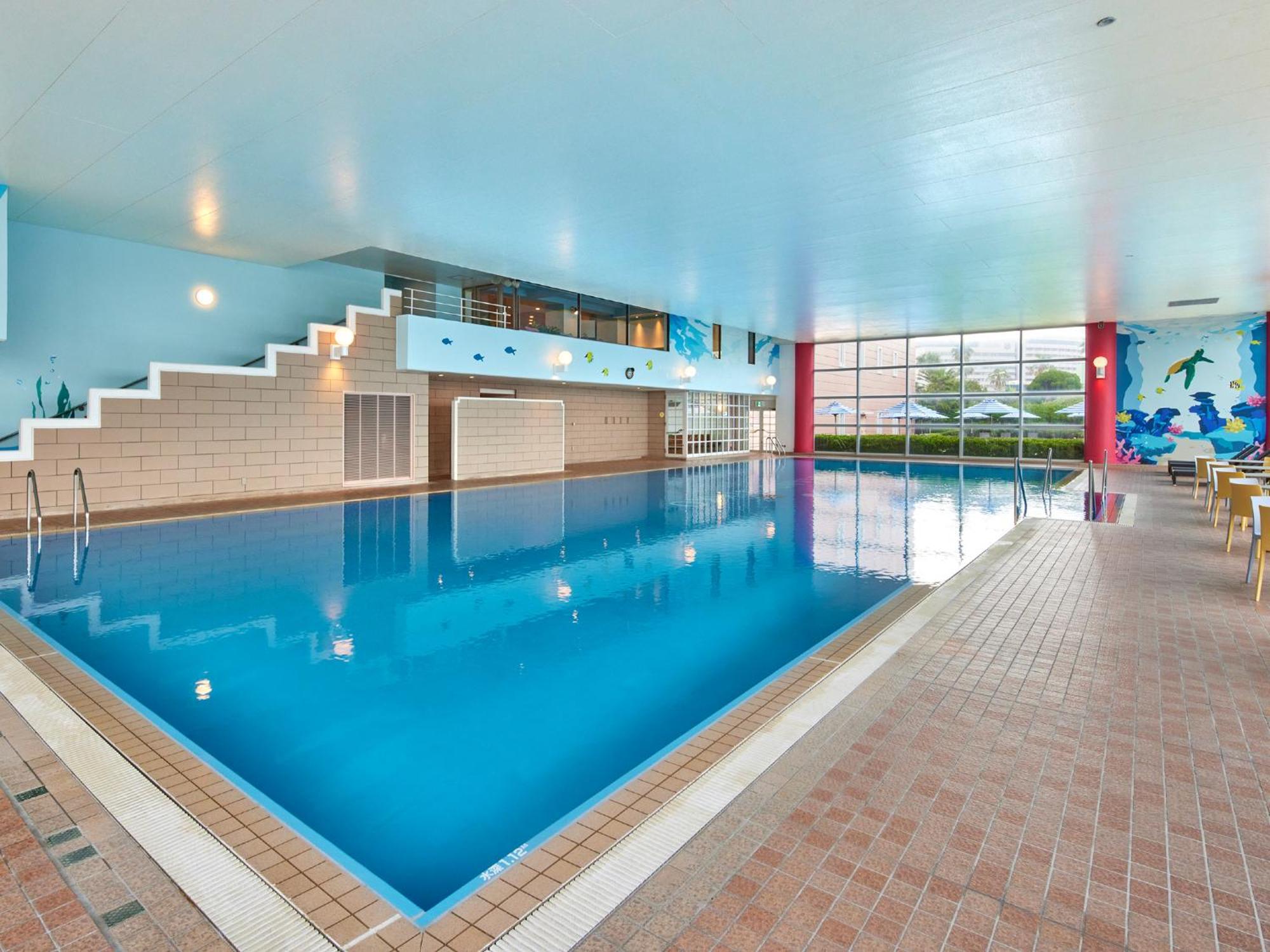 Grand Nikko Tokyo Bay Maihama Urayasu Exterior foto The photo shows an indoor swimming pool area with a spacious design. The pool has a clear blue water surface and is surrounded by a tiled deck. On one side of the pool, there are steps leading into the water, and there are large windows letting in na