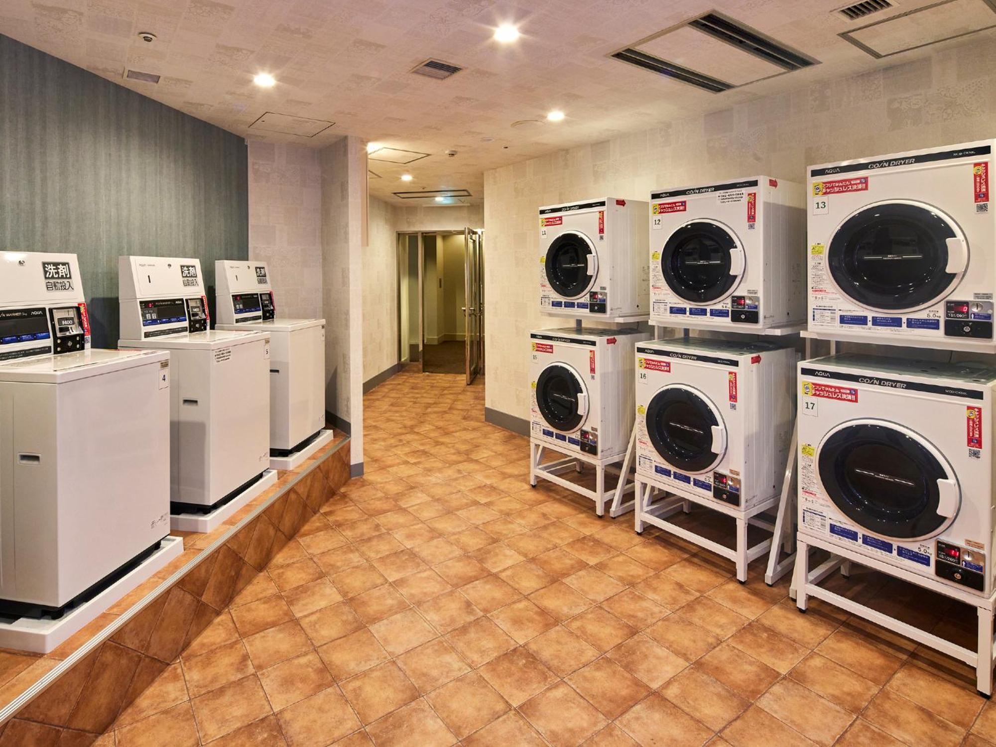 Grand Nikko Tokyo Bay Maihama Urayasu Exterior foto The photo shows a laundry room with several washing machines and dryers. On the left side, there are five white washing machines, and on the right side, there are four dryers. The machines are arranged in a clean, tiled space with a neutral-colored w