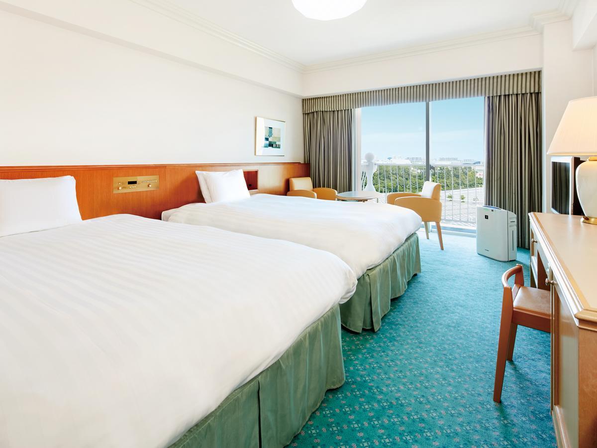 Grand Nikko Tokyo Bay Maihama Urayasu Exterior foto The photo shows a hotel room featuring two twin beds with white bedding. The walls are painted in light colors, and there’s a window that offers a view outside, letting in natural light. A small table and chairs are visible near the window, as well a